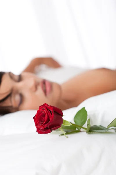 stock image Woman lying in white bed, focus on rose